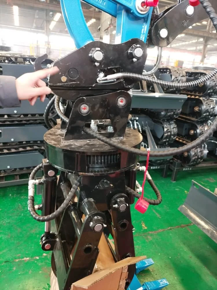 A person pointing at a large industrial robotic arm with black metal components, hydraulic hoses, and connecting bolts inside a factory with green flooring and machinery in the background.